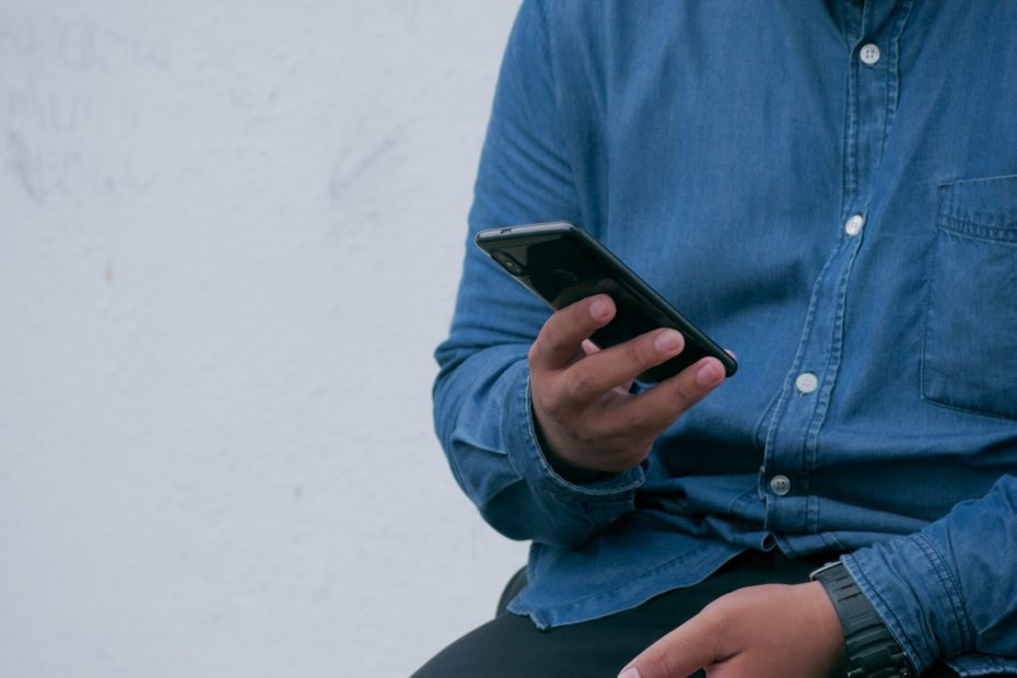 person in blue denim jacket holding smarthone